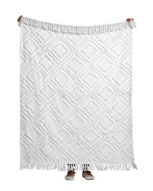 Full view of ivory tufted throw blanket with diamond pattern and fringe, held up