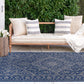 Lifestyle view of navy and gray medallion outdoor rug by daybed with striped pillows