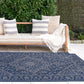 Lifestyle view of navy and gray medallion outdoor rug by daybed and hedge