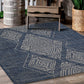 Lifestyle view of blue outdoor rug with ivory diamond medallions on wooden deck with bench