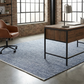 Lifestyle view of denim blue woven indoor outdoor rug under desk in loft office