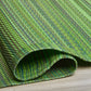 Corner close-up of rolled green striped outdoor rug showing reverse