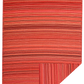 Full view of red and orange striped outdoor rug with corner folded to show reverse