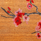 Texture close-up of red and pink cherry blossoms on gray branch in coir doormat