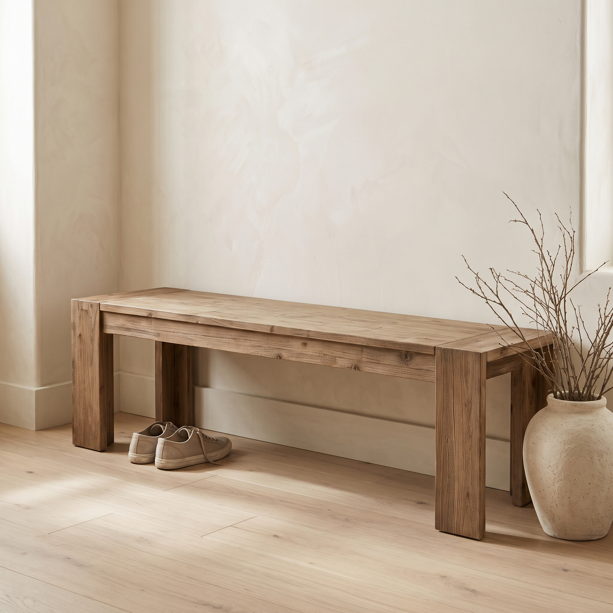 Dune solid acacia bench in Weathered Natural against a cream hallway wall, with sneakers below and a vase of branches