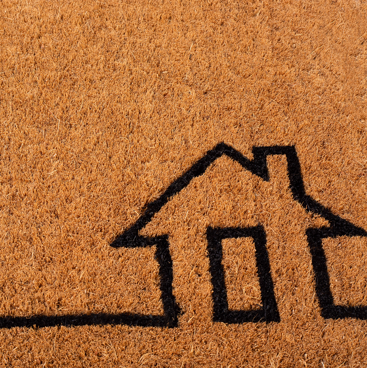 Texture close-up of black house outline on natural coir doormat