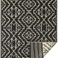 Full view of black and cream tribal outdoor rug with corner folded back to show reverse