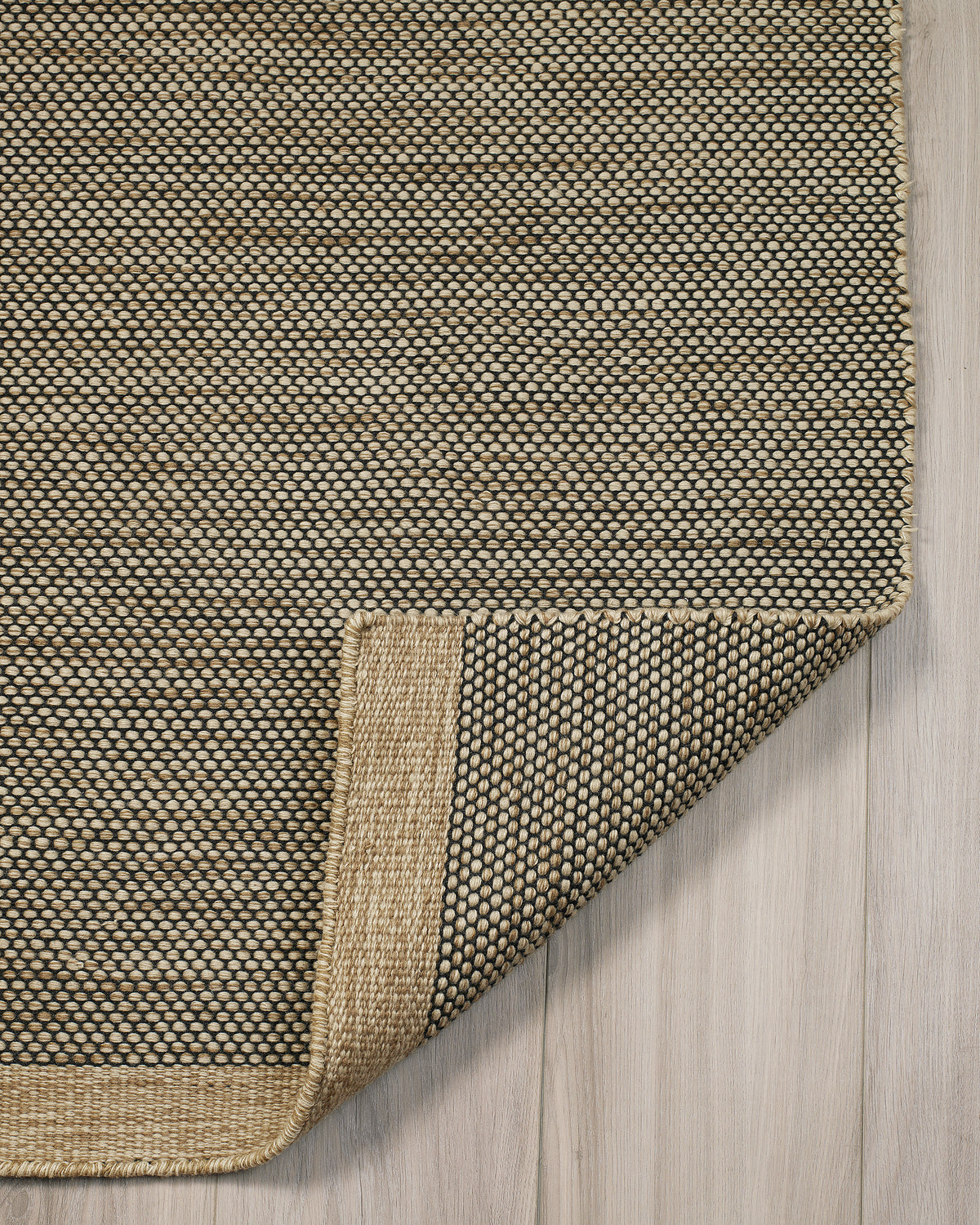 Black & Beige Outdoor Rug, folded corner showing woven texture