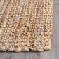 Corner close-up of natural chunky weave jute area rug braided edge