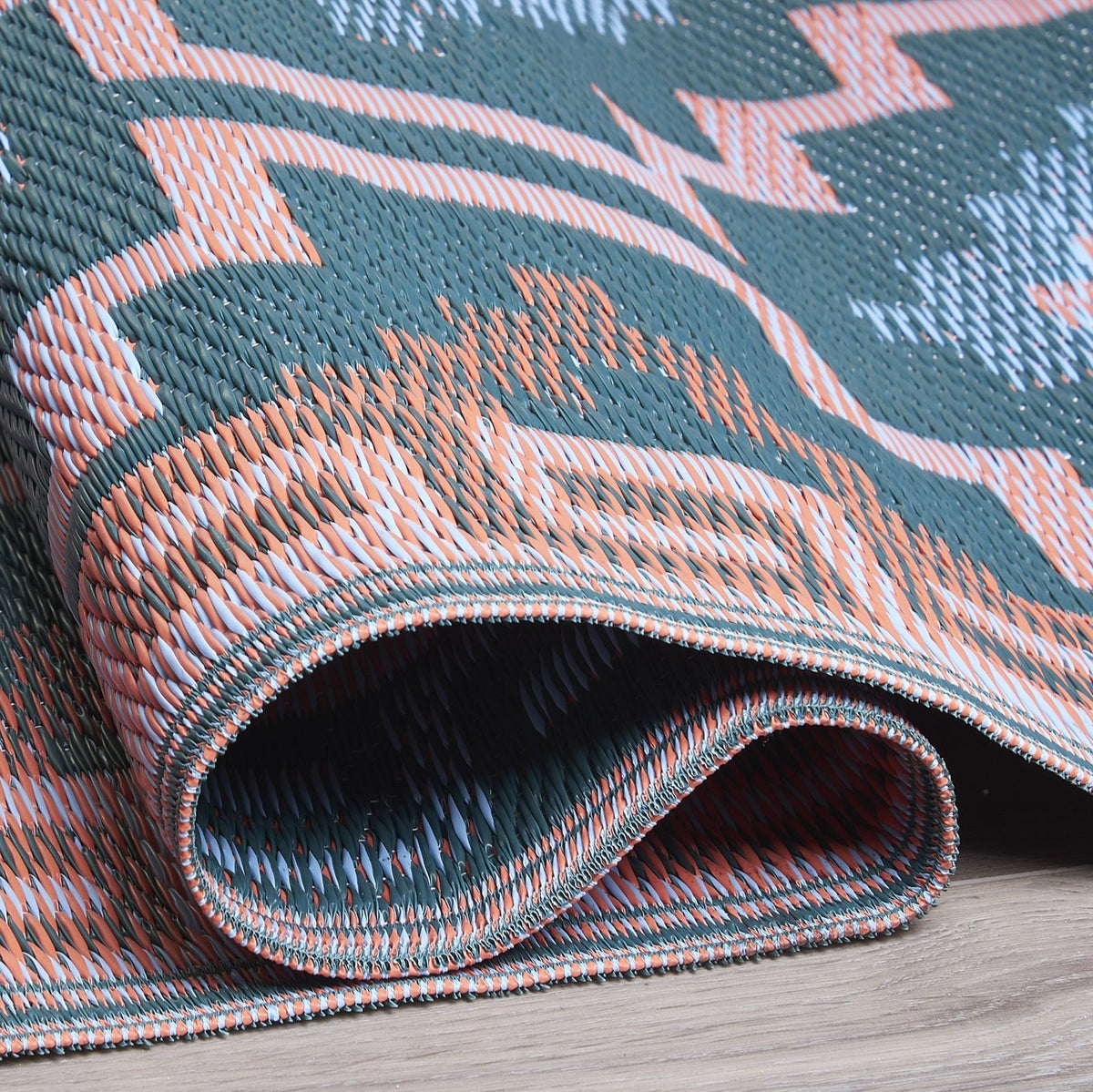 Texture close-up of green diamond outdoor rug with rolled edge