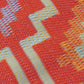 Texture close-up of orange and violet diamond outdoor rug showing woven strands