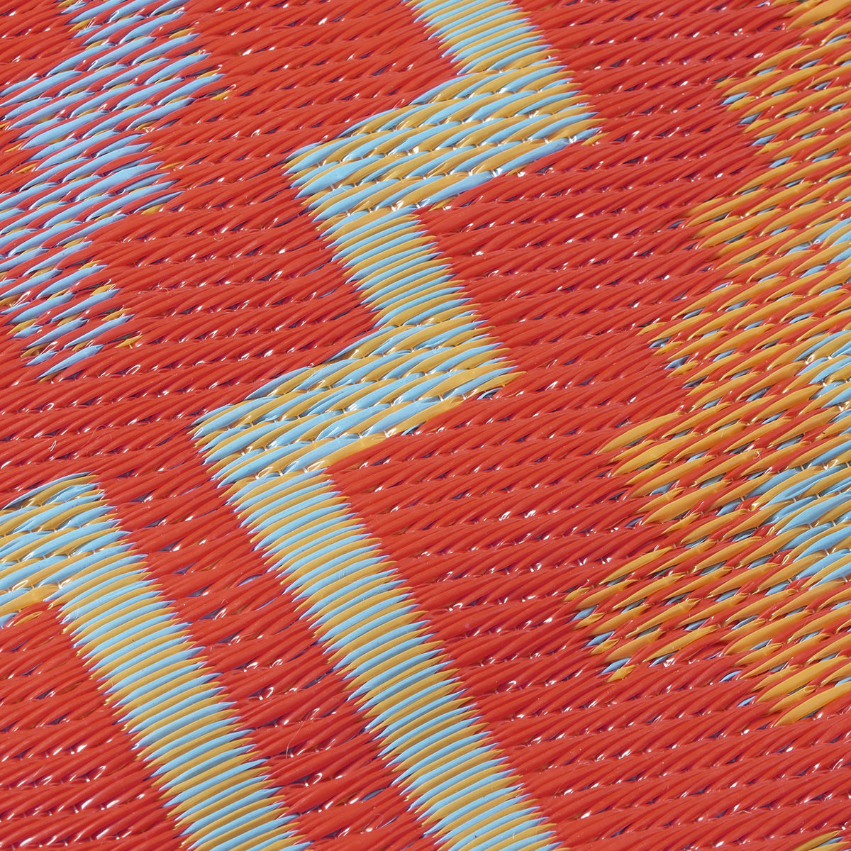 Texture close-up of orange and violet diamond outdoor rug showing woven strands