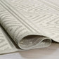 Corner close-up of rolled beige and ivory chevron outdoor rug showing reverse