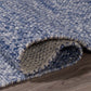 Texture close-up of denim blue woven indoor outdoor rug rolled to show chunky weave