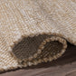 Texture close-up of sand woven indoor outdoor rug rolled to show chunky weave