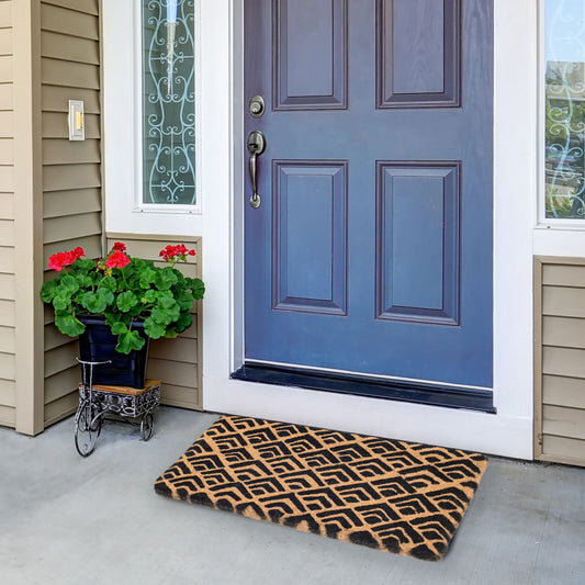 Lifestyle view of thick block print coir doormat at blue front door by potted geraniums
