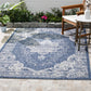 Lifestyle view of blue and ivory medallion outdoor rug on patio by wooden table