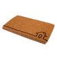 Angled view of thick natural coir doormat with black line-drawn house outline showing deep pile