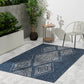 Lifestyle view of blue outdoor rug with ivory diamond medallions on patio by metal chair
