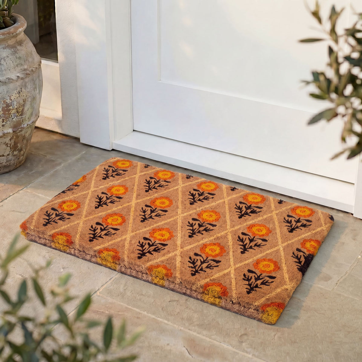 Lifestyle view of marigold lattice coir doormat at white front door on stone patio