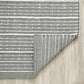 Reverse side of charcoal and white striped indoor outdoor rug with corner folded back