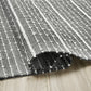 Texture close-up of charcoal and white striped indoor outdoor rug rolled to show weave