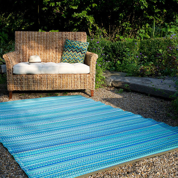 Video of the Cancun turquoise and moss green striped outdoor rug on a patio