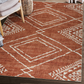 Lifestyle view of orange and ivory diamond machine washable area rug under wooden chair