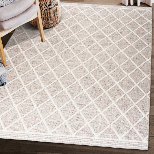 Lifestyle view of beige and ivory lattice machine washable area rug beside woven chair