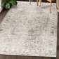 Lifestyle view of beige and ivory medallion machine washable area rug under wooden chair