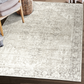 Lifestyle view of beige and ivory traditional machine washable area rug beside woven chair